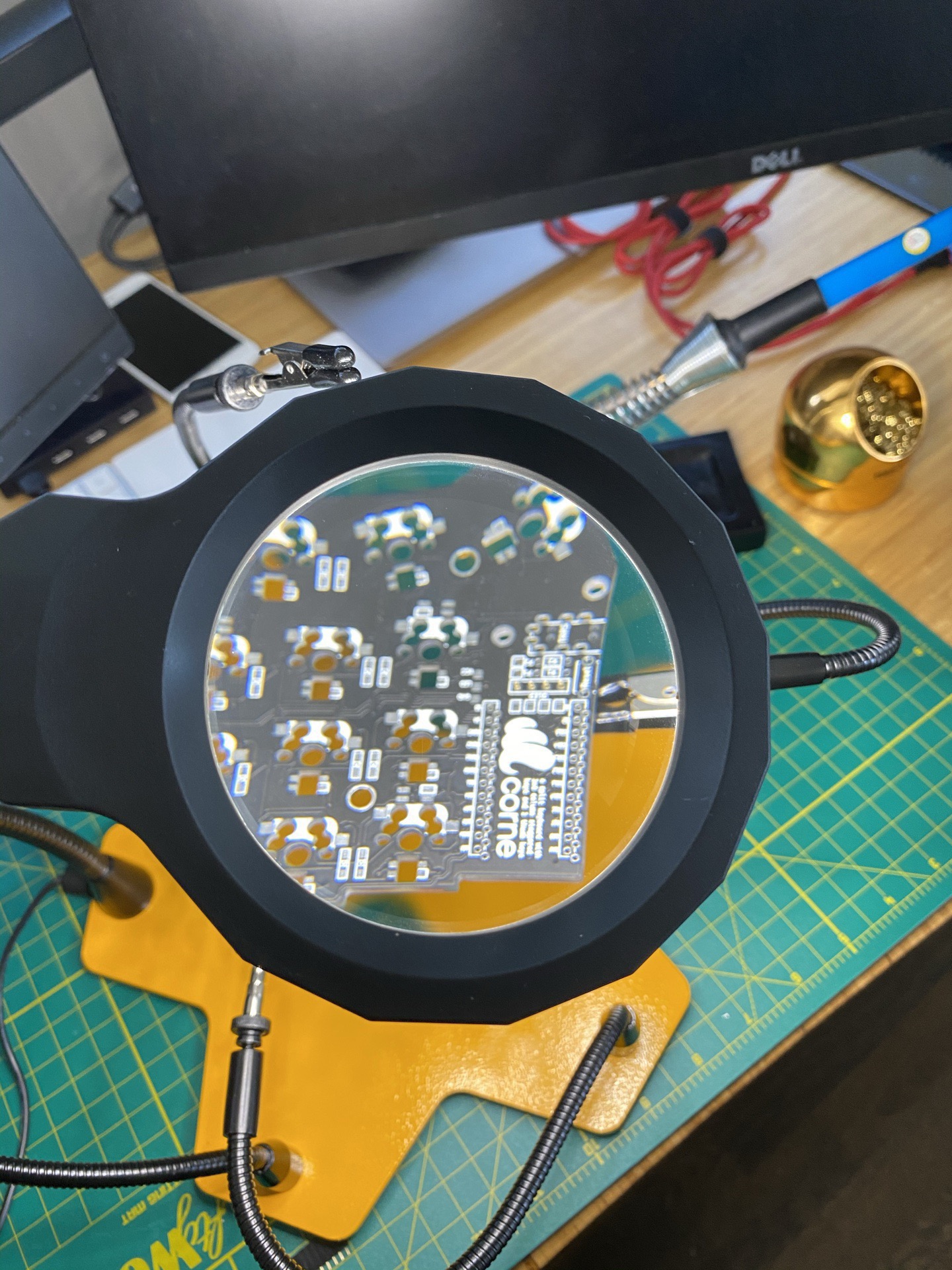 Close-up of the Corne PCB seen through the round magnifying lens, with the 'corne' silkscreen logo and surface-mount diodes clearly visible.